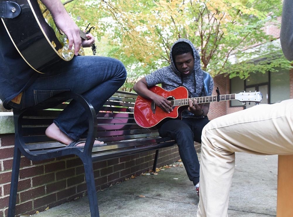 Summer camp students participate guitar jam session outside