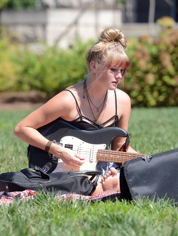 Guitar student playing guitar on the grass