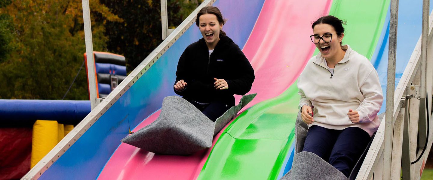 Students ride down a slide during Fall Festival