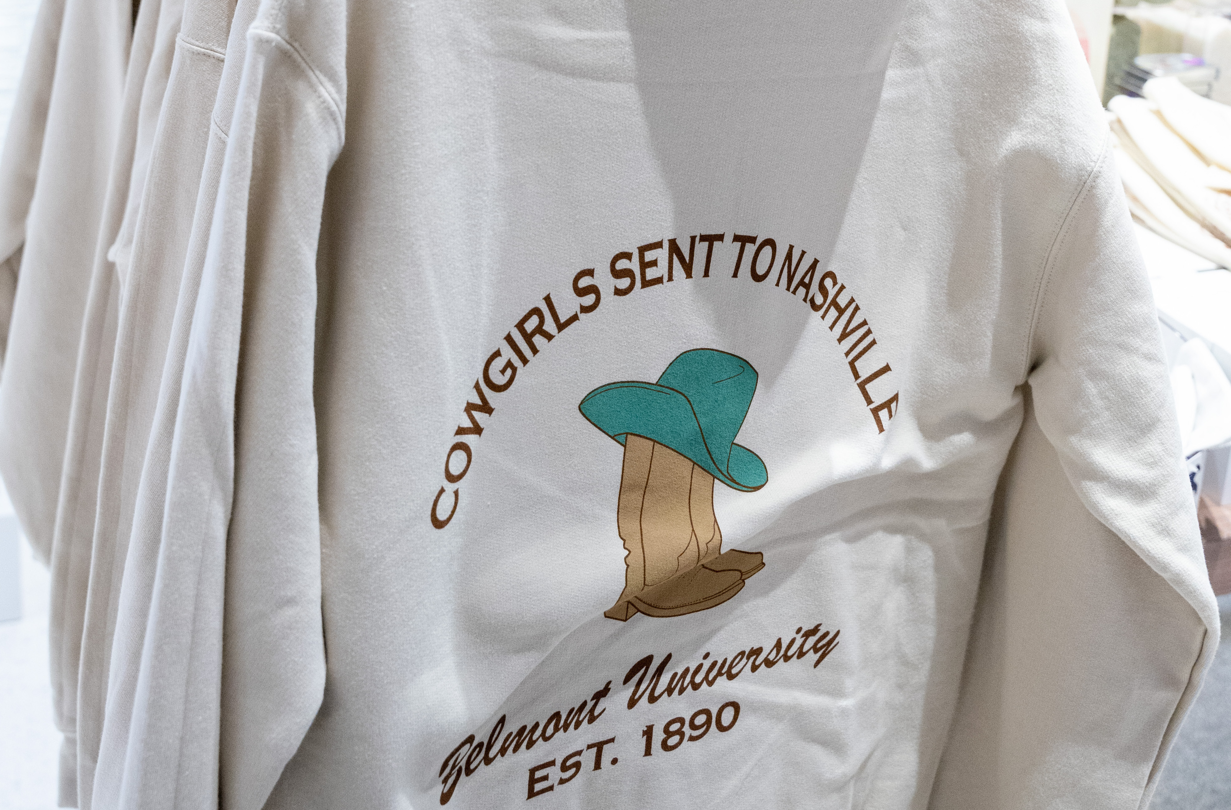 Image of a tan sweatshirt that says "Cowgirls sent to Nashville" designed by O'More students