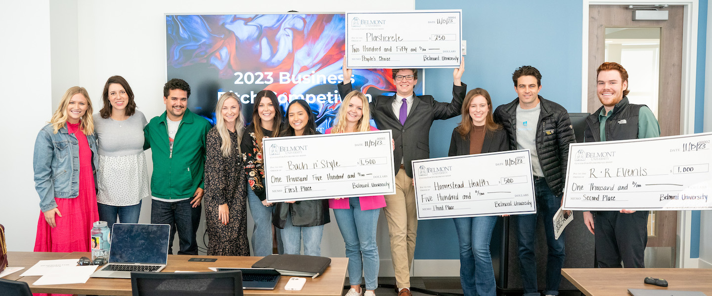 Business pitch winners, organizers and judges with giant checks