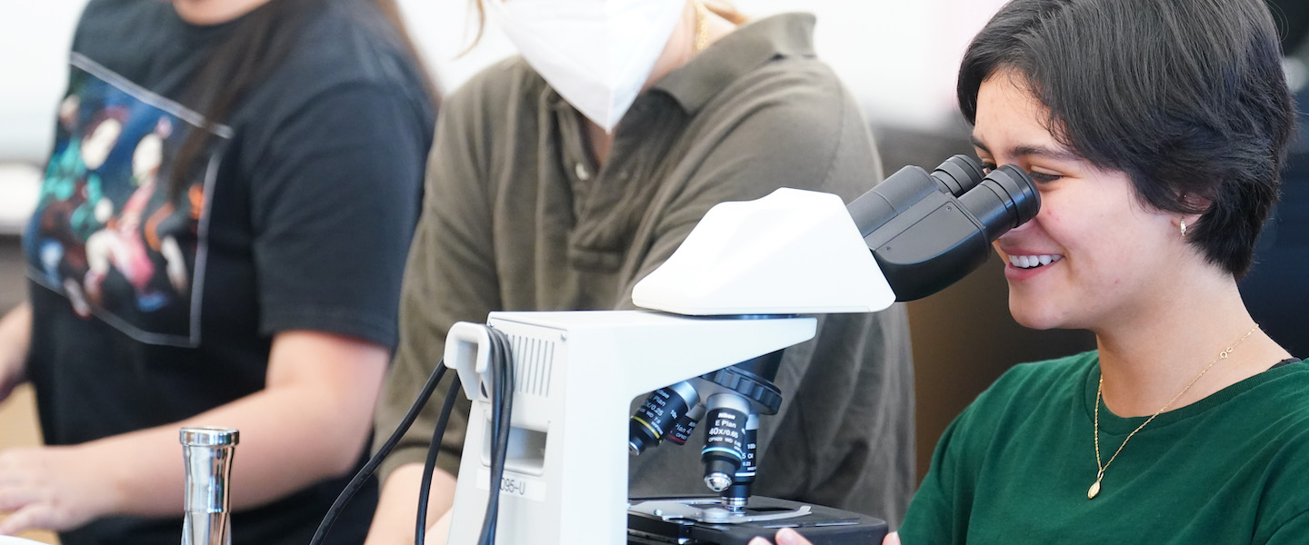 High School student looks into a microscope