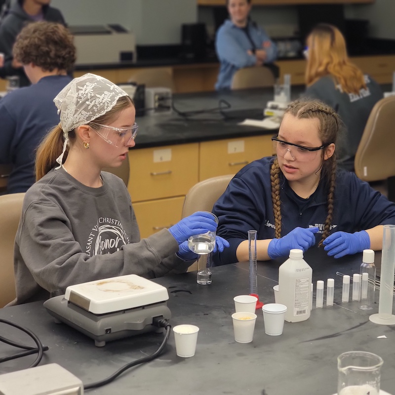 Two high school students measure components to make their own hand sanitizer