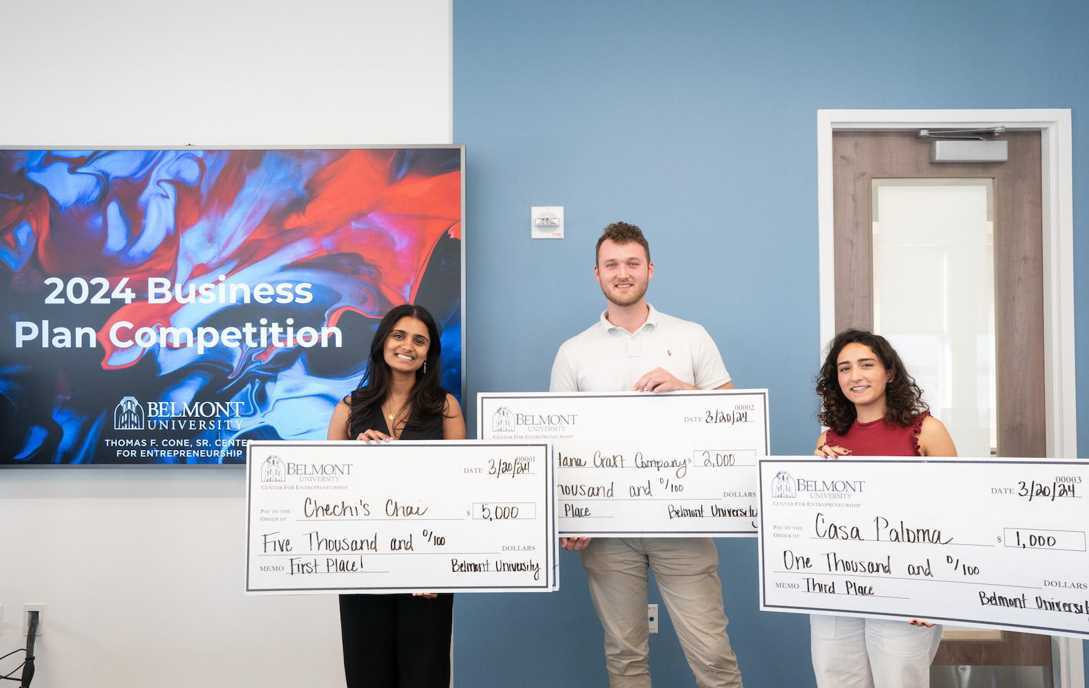 Winners of Business Plan Competition pose with giant checks