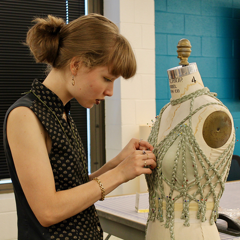 Student pinning fabric onto a dress form