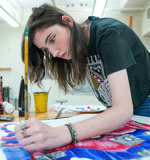 Teen girl painting a brightly colored abstract piece