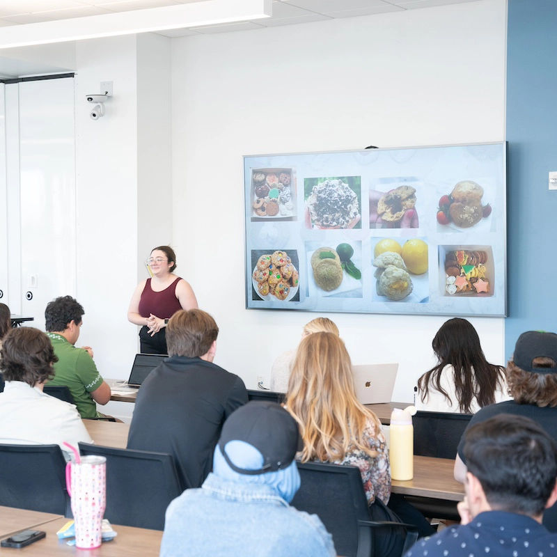 Female student presenting a powerpoint to a room full of people