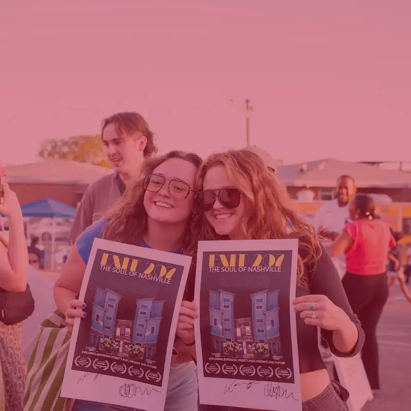 two girls smiling holding up posters for “Exit 207”