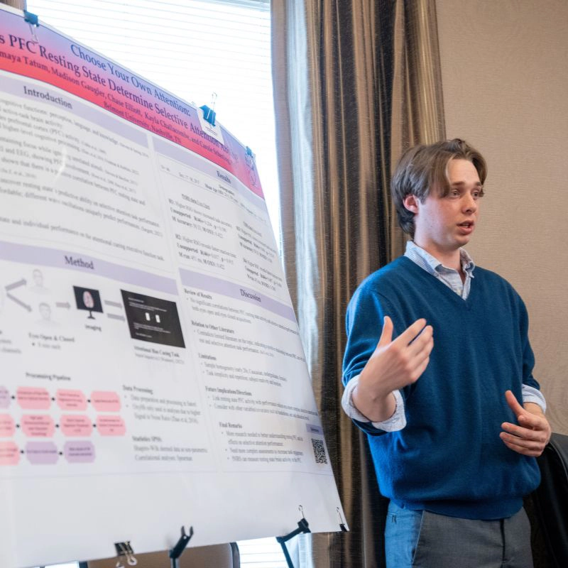 Student stands next to his poster