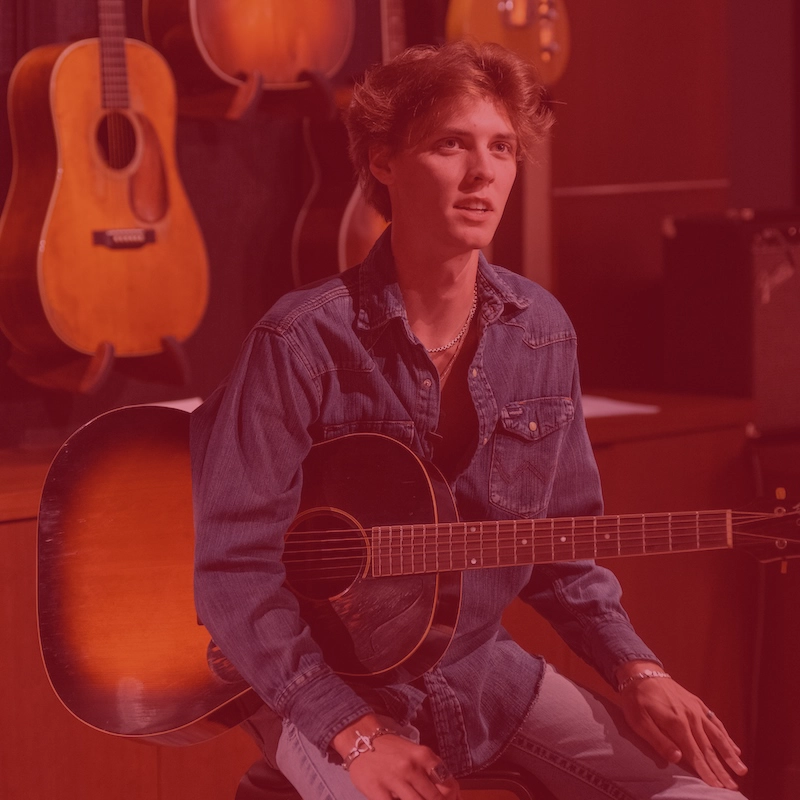 True Youngblood sits on a stool within The Gallery of Iconic Guitars at Belmont