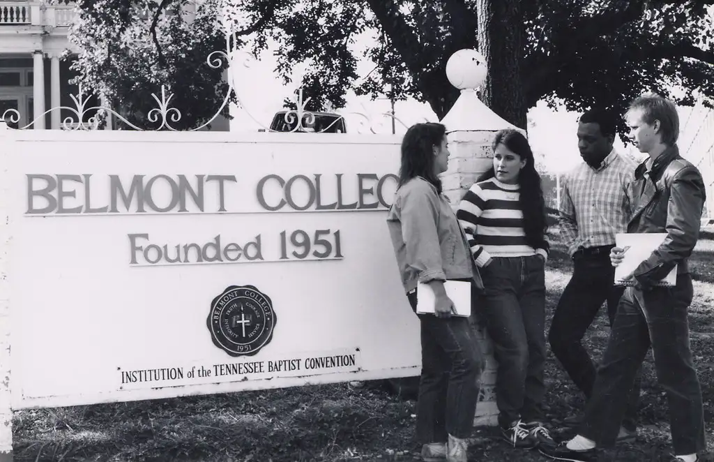 Outdoors photo of two men and two women standing in front of a sign that reads Belmont College, Founded 1951, Institution of the Tennessee Baptist Convention with the school crest above that.