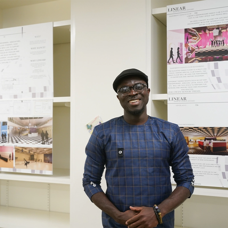 A picture of a man smiling and standing in front of a wall