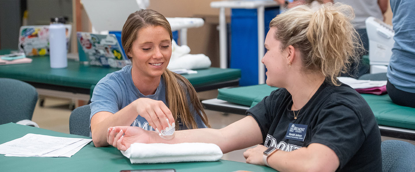 Two OT students working in a lab with one student icing the other's arm.