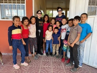 Pharmacy Mission trip photo of 2 Belmont students with young children.