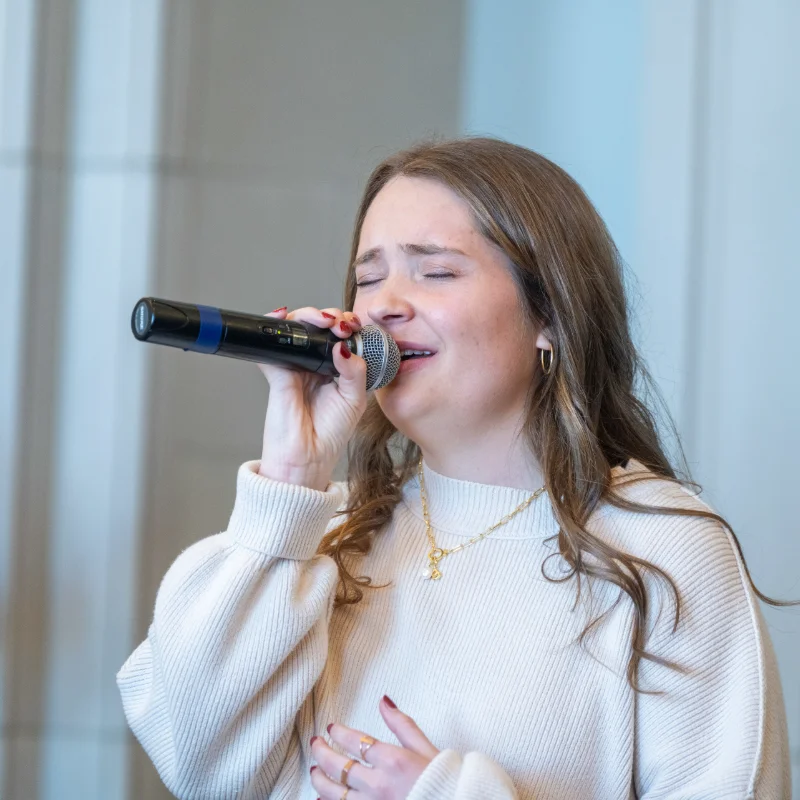 Female vocalist singing with emotional expression, eyes closed, during a worship.