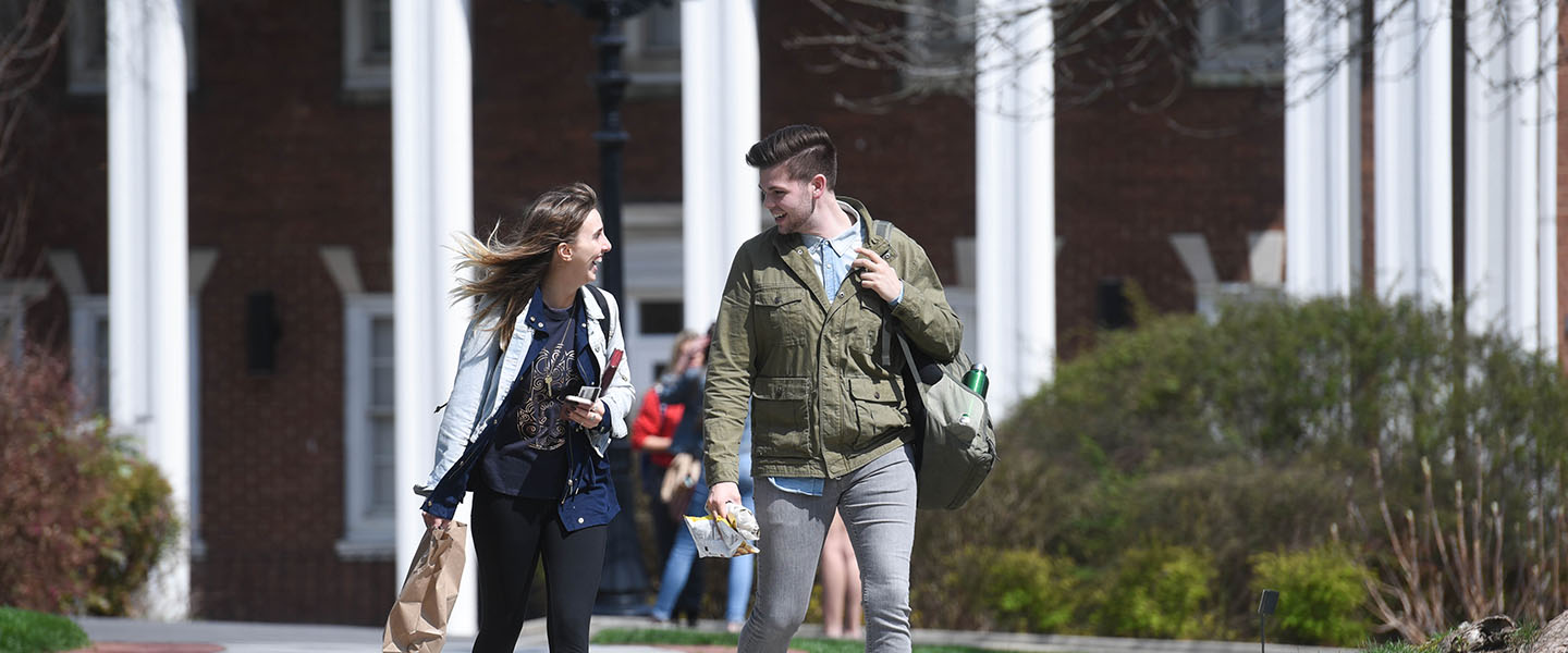 Two students talking as they walk across campus