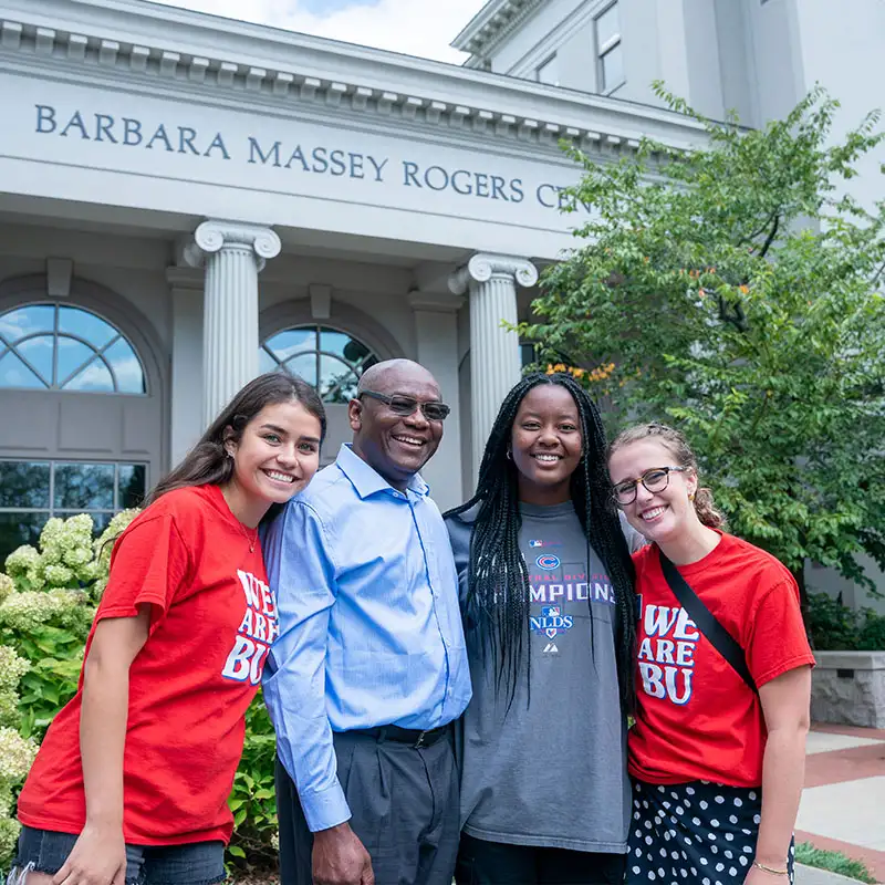 Two Bruin Recruiters, a father and his daughter stand in front of the Massey Rogers Center