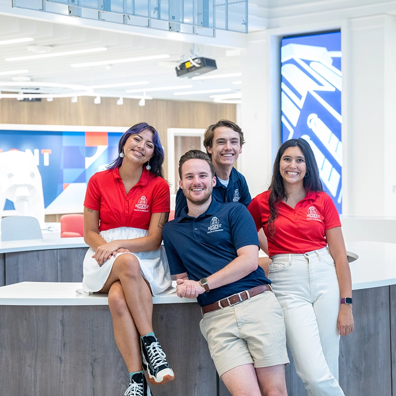 A group of Belmont Admissions Counselors pose in front of a Welcome desk