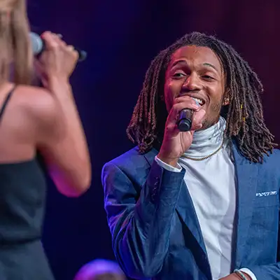 A Belmont University student sings into a microphone during a live performance onstage.