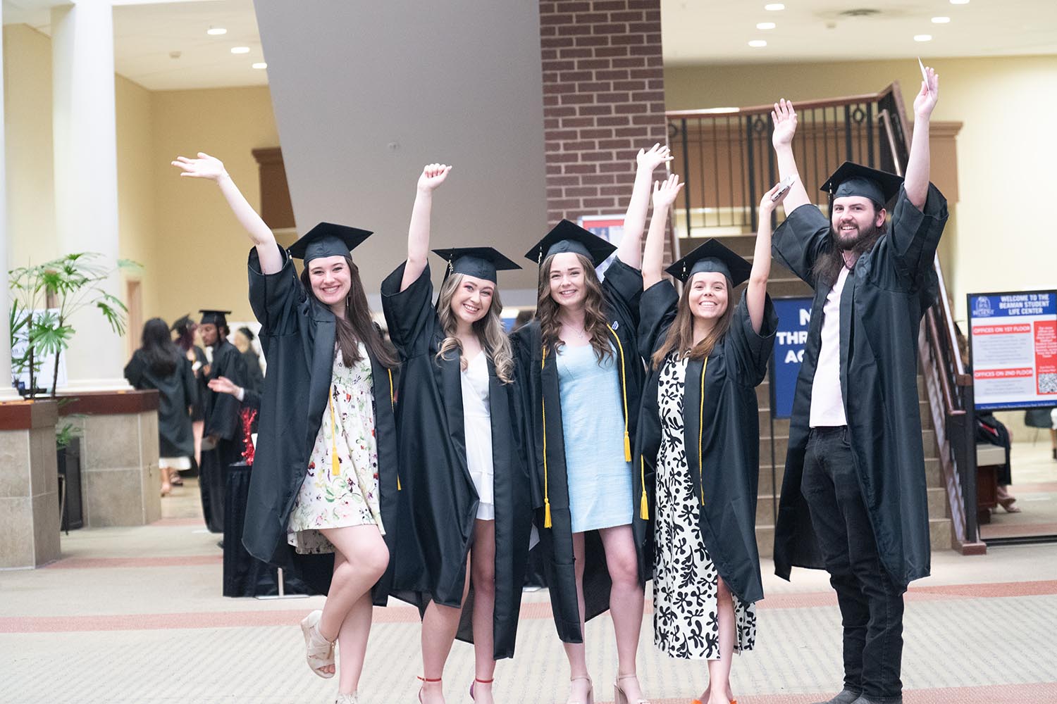 Students in caps and gowns posing for a picture in Beaman Student Life Center while waiting for their graduation ceremony start