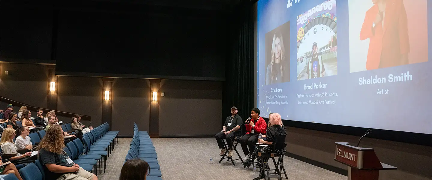 An indoor picture of a panel of speakers talking to a group in the motion pictures theatre