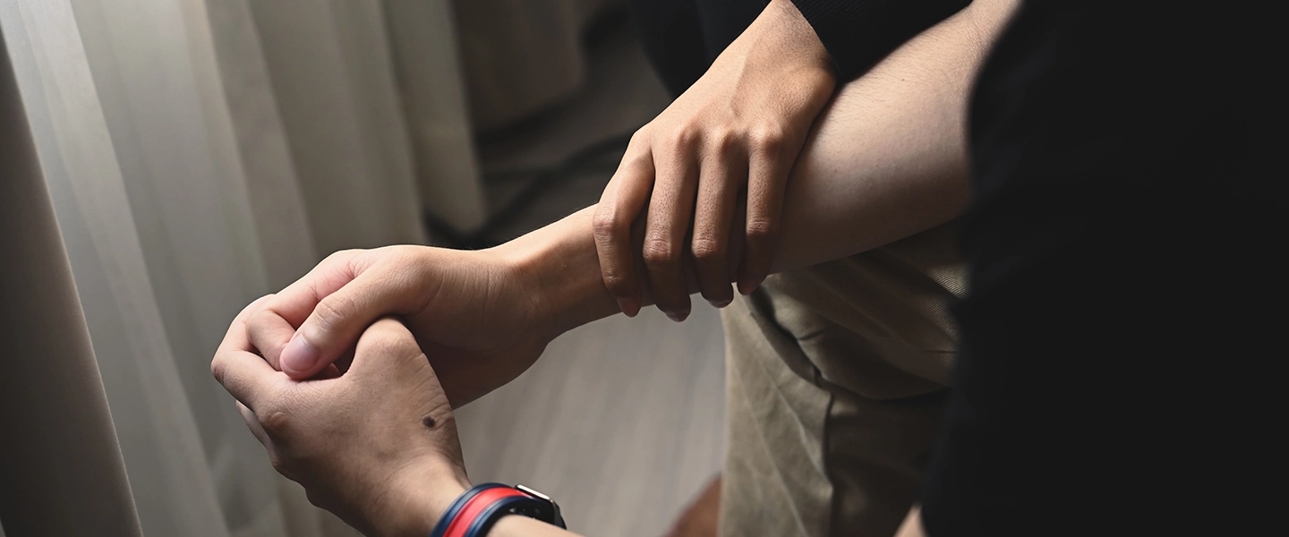 A photo of a husband's hand clasped with this wife's hand on his arm.