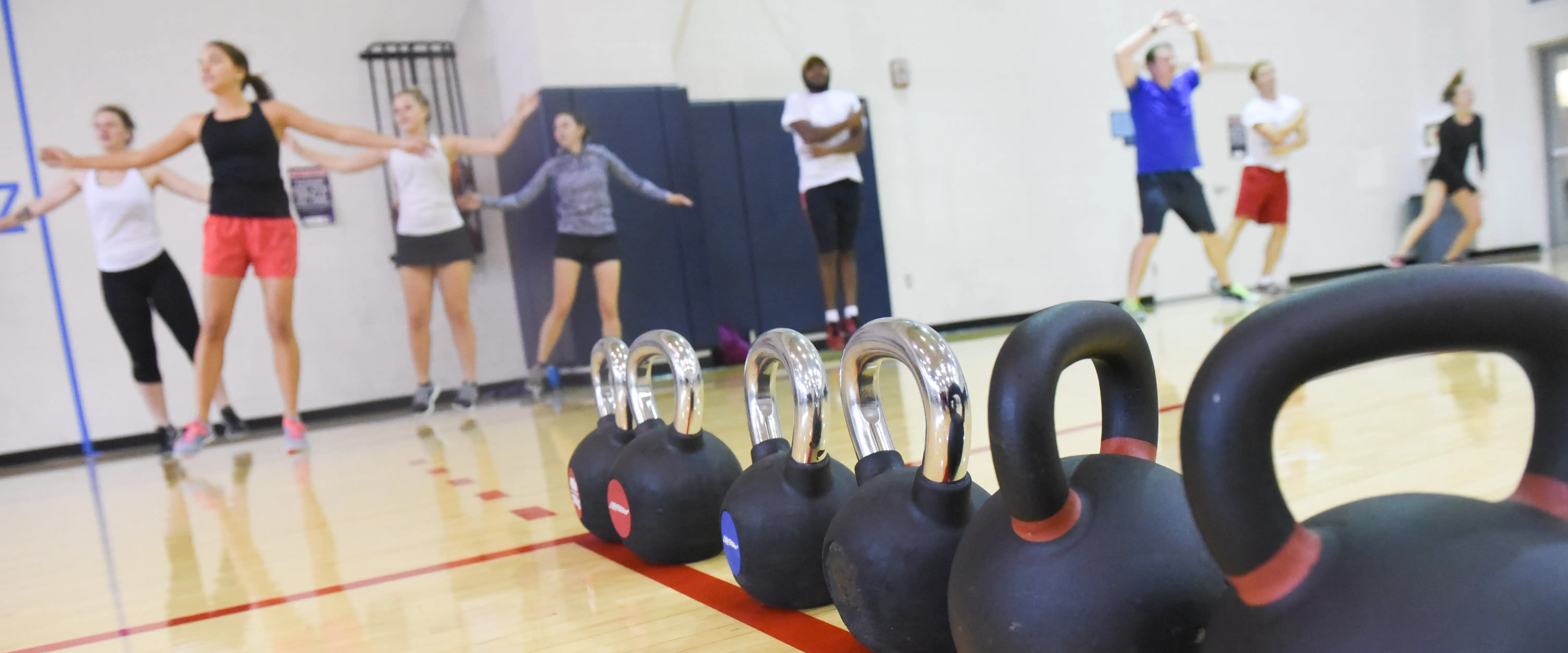 Close up of kettle bells with students doing jumping jacks