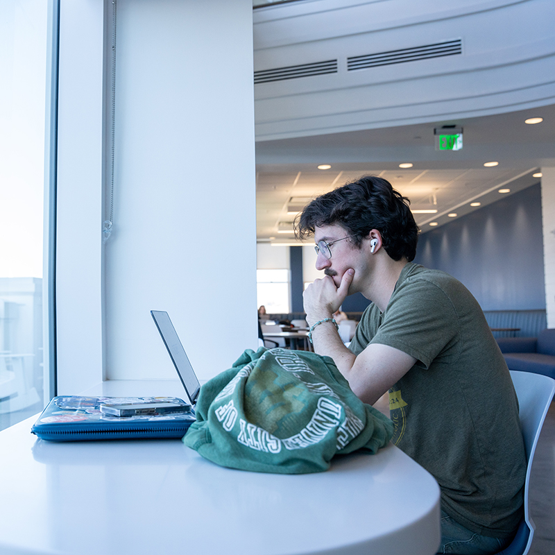A student looking at a laptop in a well light building on Belmont's campus