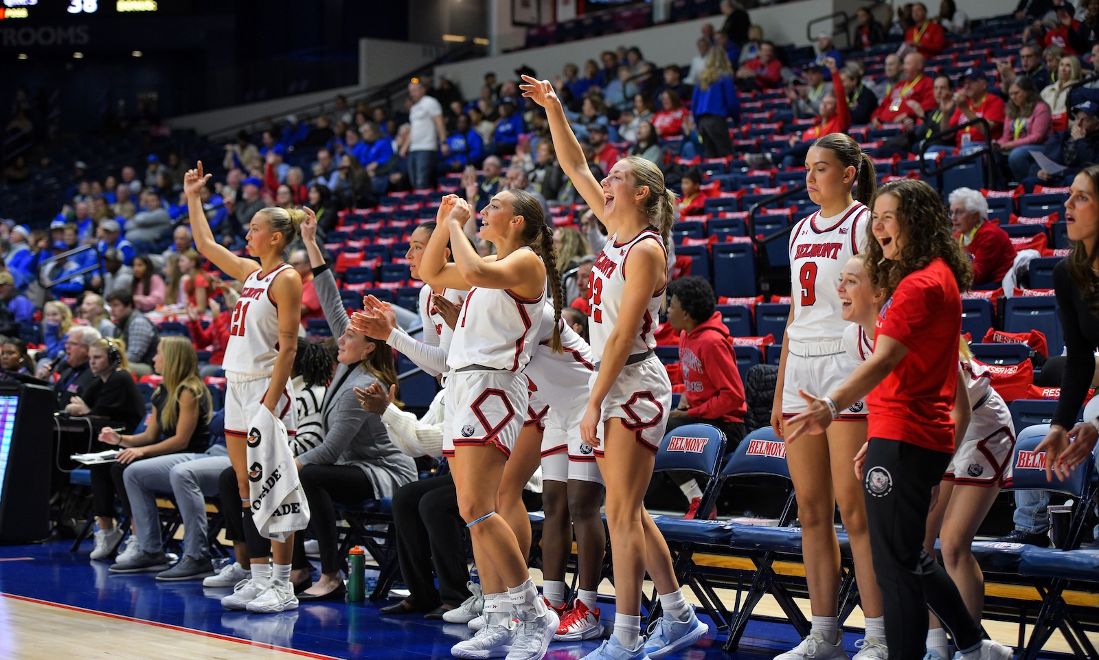 The women's basketball team cheers from the bench during a game.