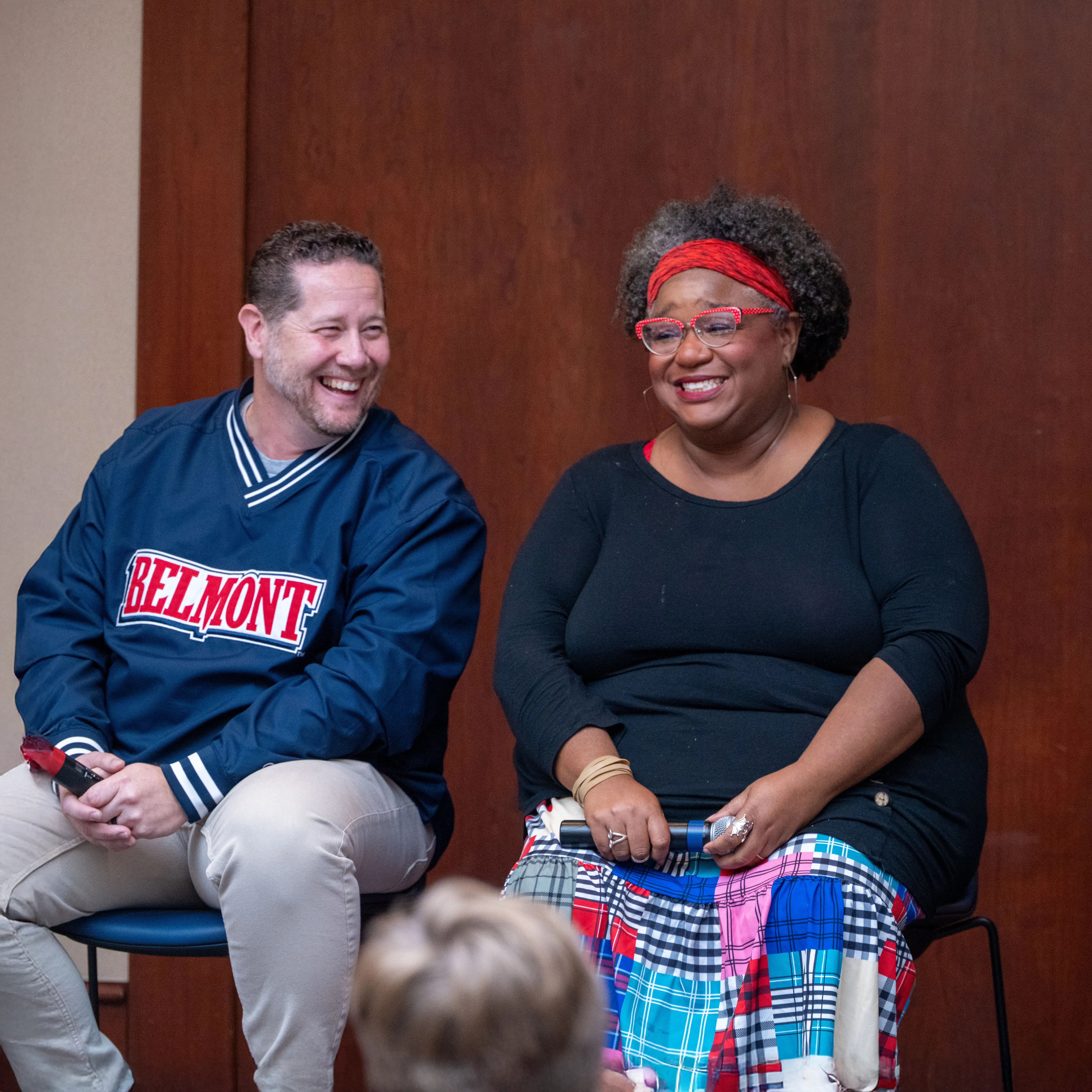 Two speakers sit side by side during a campus conversation, smiling and engaging with an audience during a Belmont University event.