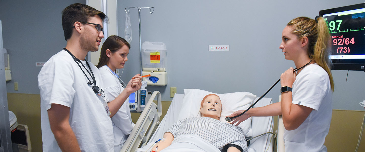 Three nursing students working with a patient simulator