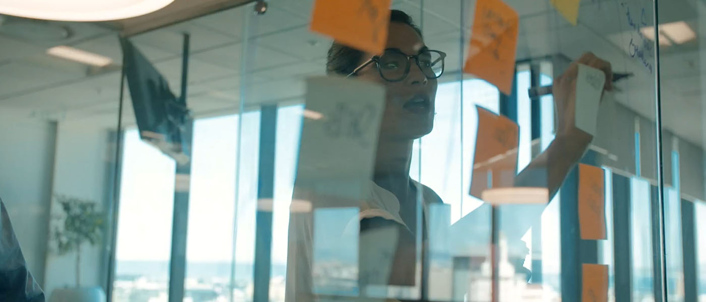 Woman writes on a piece of glass covered in sticky notes