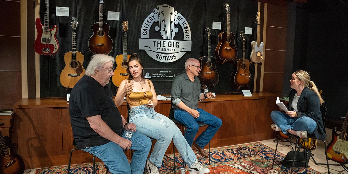 Group of people sitting in chairs having a discussion with in the GIG guitar museum 