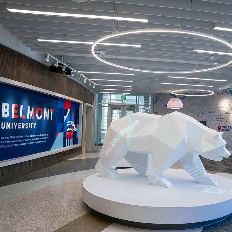 The 3D bear statue in the Jack C Massey Center with #itsBRUINtime projected on the side and a Belmont University mural behind it.