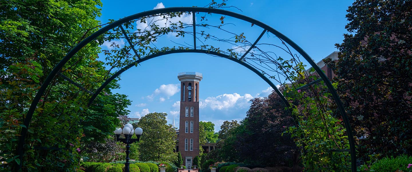 The bell tower under an archway on a sunny day on the historic side of campus 