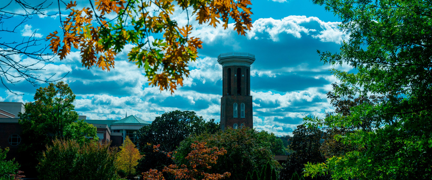 The Bell Tower on a cloudy day though the orange leaves of a tree