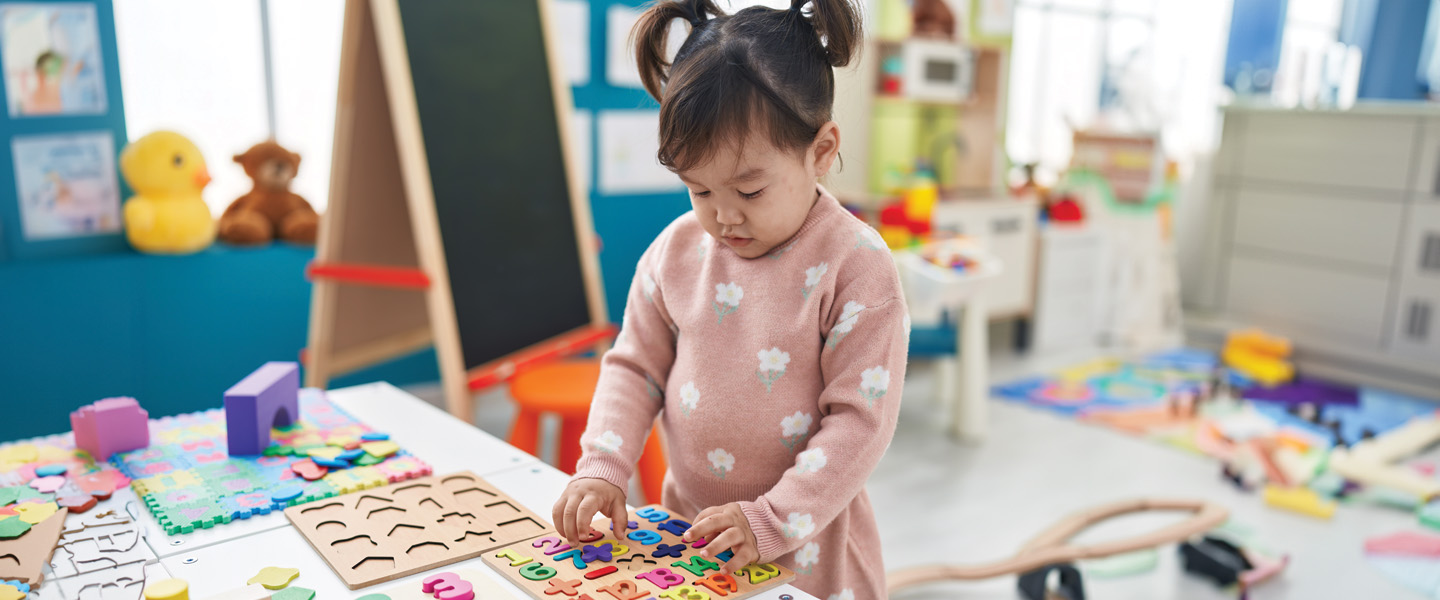 A little Chinese girl plays with blocks and letters