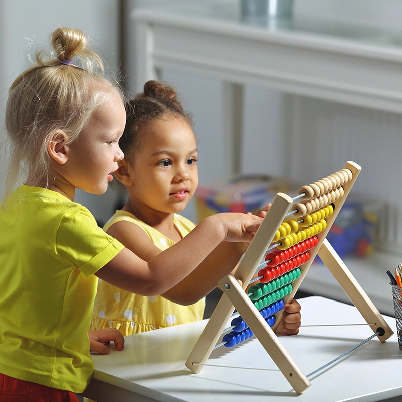 Two diverse preschoolers playing with an abacus.