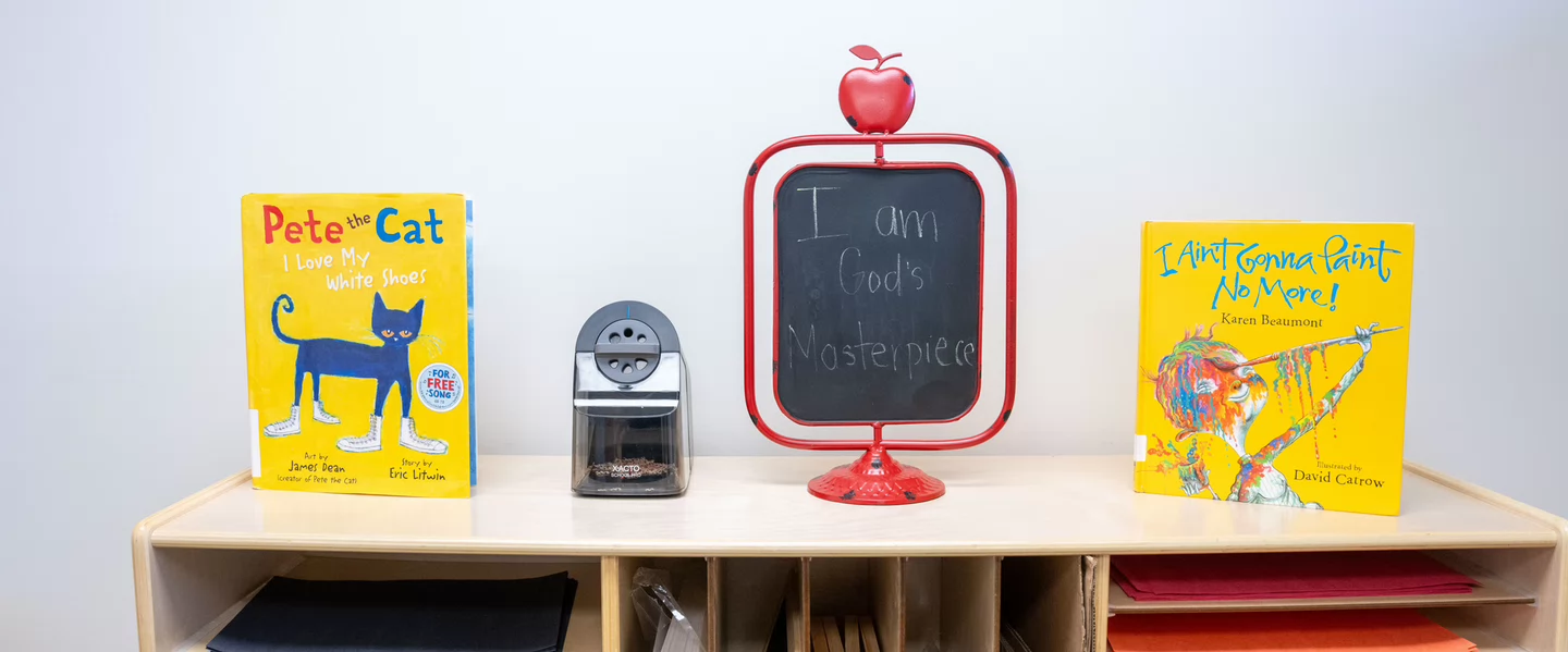Children’s books displayed beside a small chalkboard sign reading “I am God’s masterpiece.”