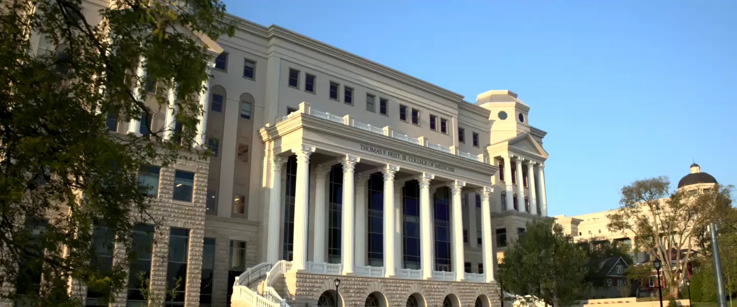 The Thomas F. Frist, Jr. College of Medicine at Belmont University is pictured from an angled view, showcasing its grand, classical architecture. Tall white columns line the front of the building, supporting an ornate façade.