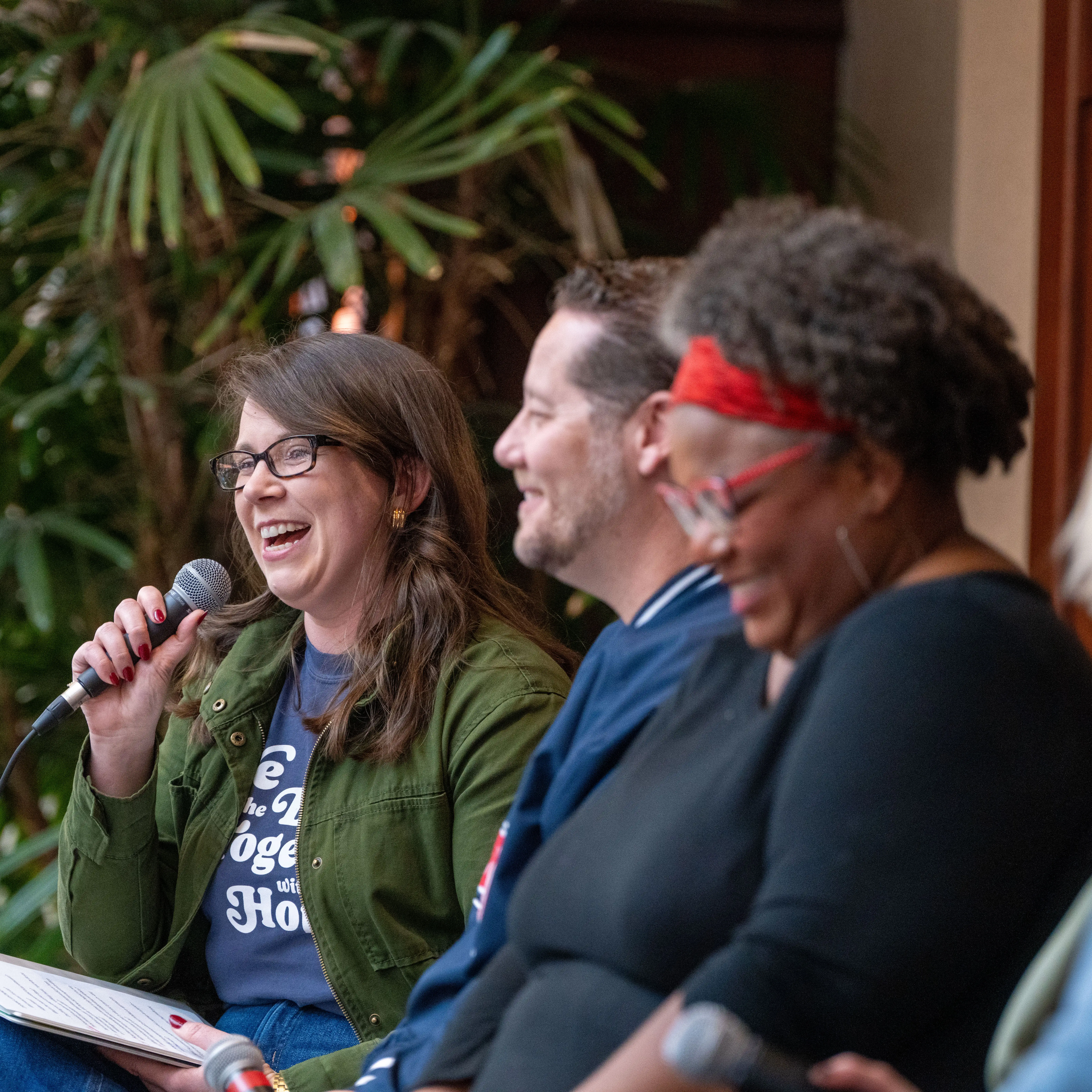Faculty and staff participate in a panel discussion indoors, smiling and speaking into microphones during a Belmont University community event.