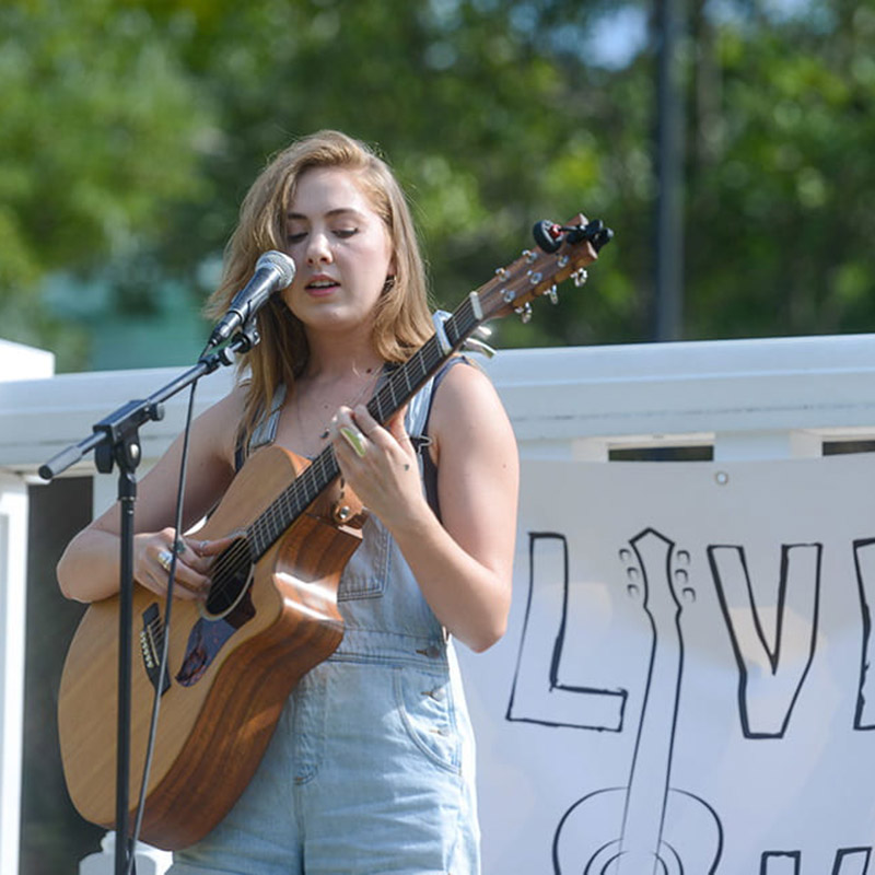 Student playing guitar outside on lawn during live on the lawn