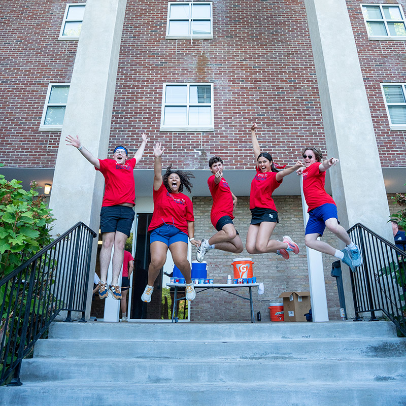 Orientation leaders jumping and cheering in the air during move in