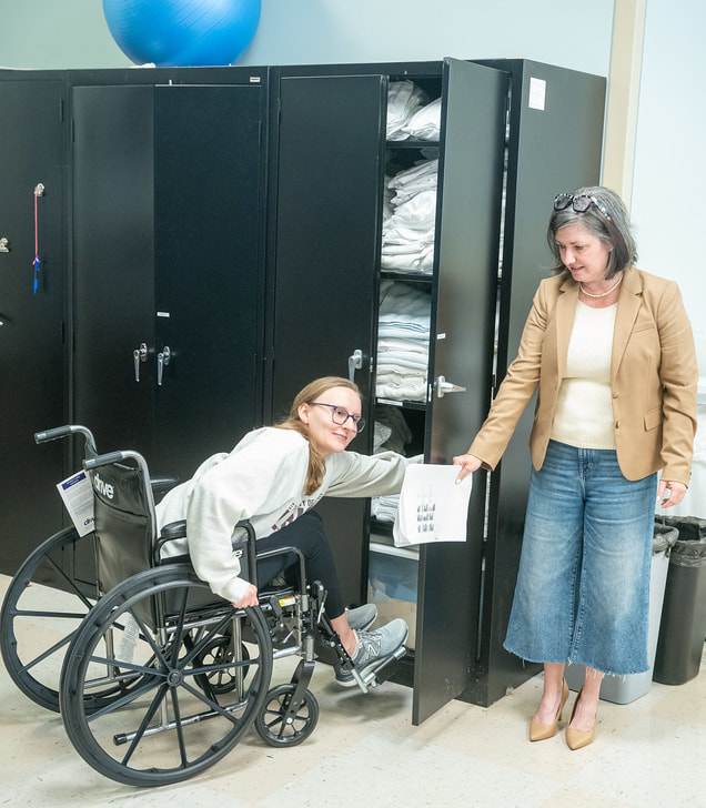 OT Student in a wheel chair testing opening a door to a cabinet in the home health lab