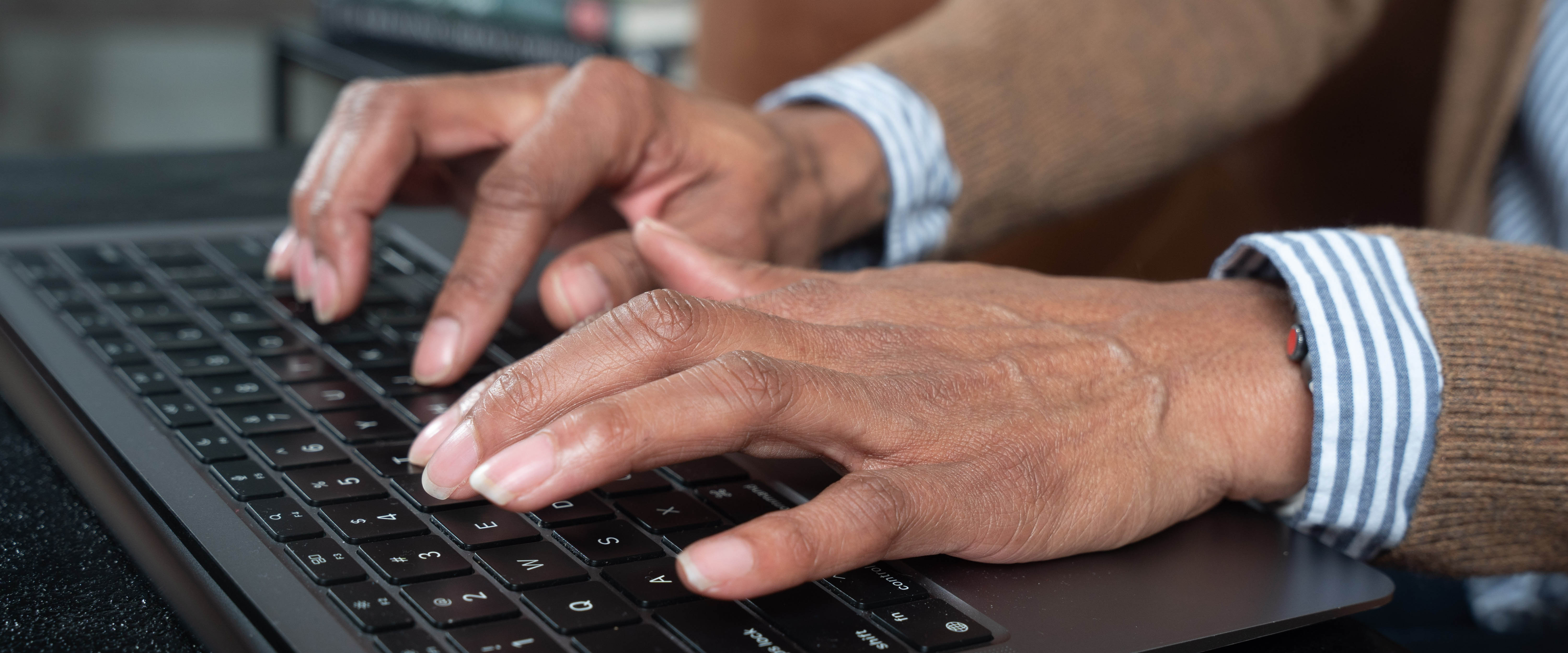 A close-up of hands typing on a keyboard