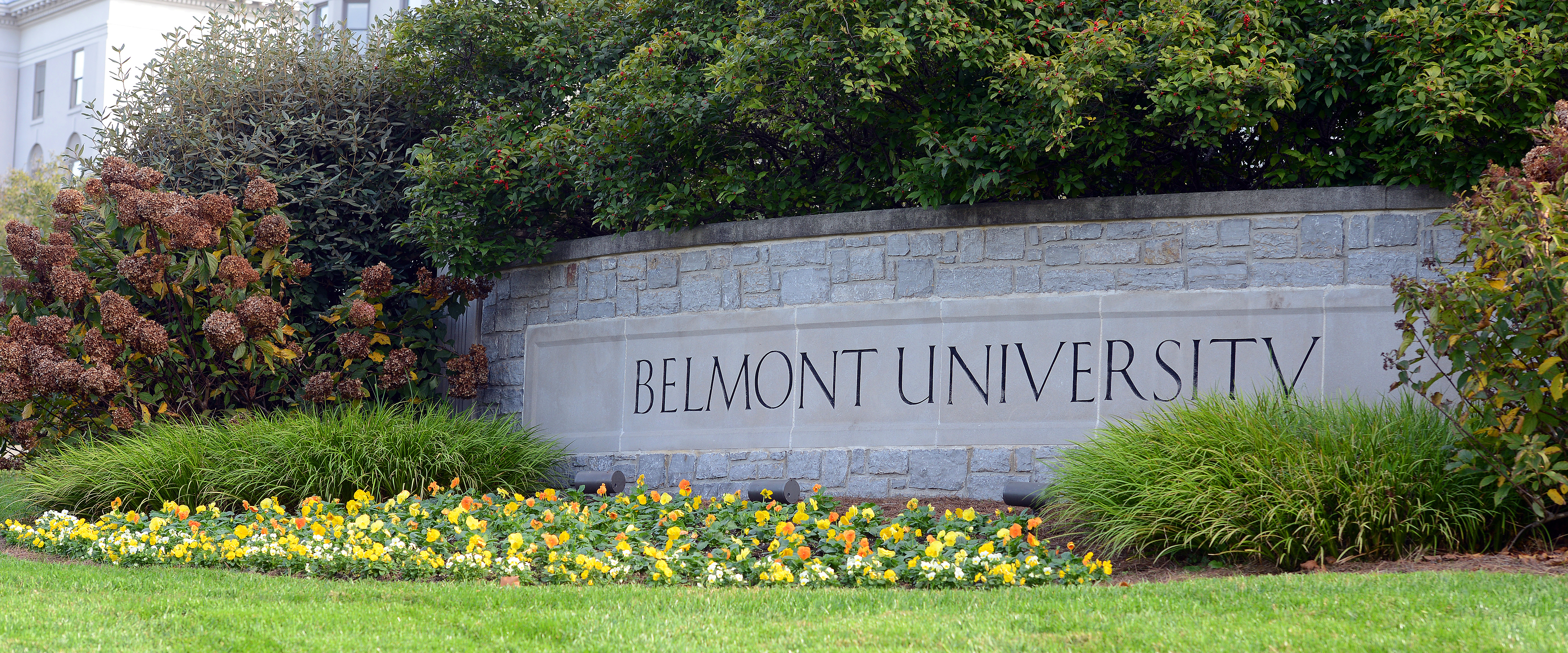 Belmont University stone sign outside on a sunny day with flowers blooming