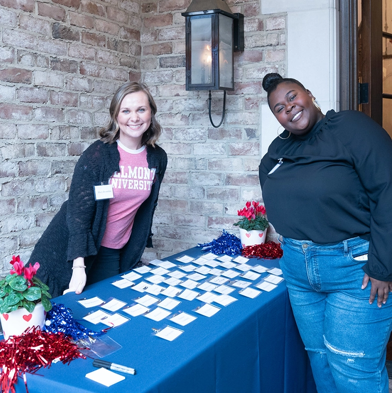 A Presidential Fellow poses at a table with a university staff member