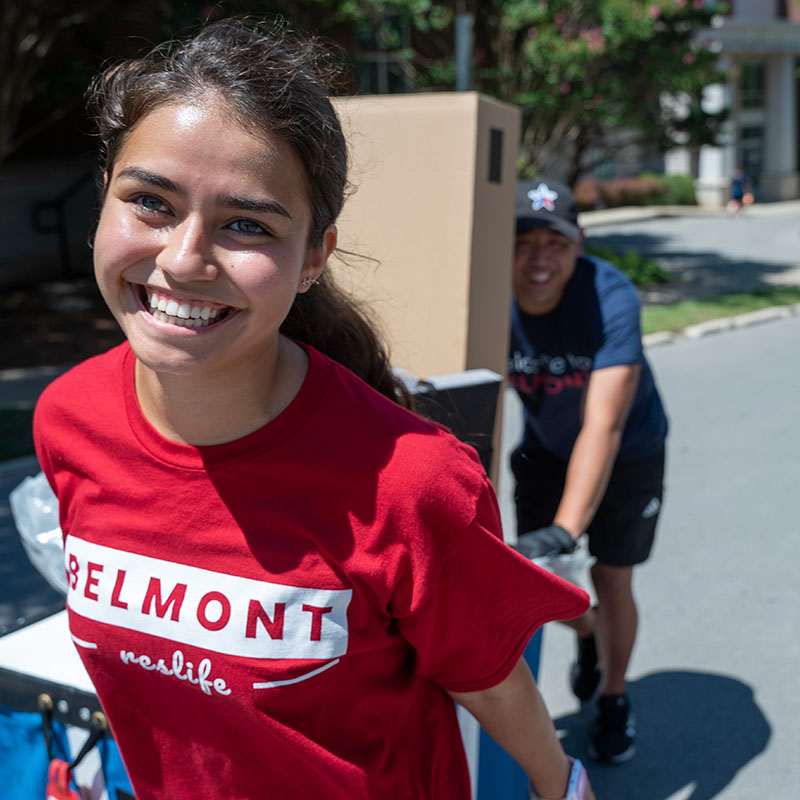 Female student pulling a cart with a box on move-in day