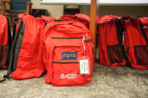 Group of red backpacks sitting together on the floor