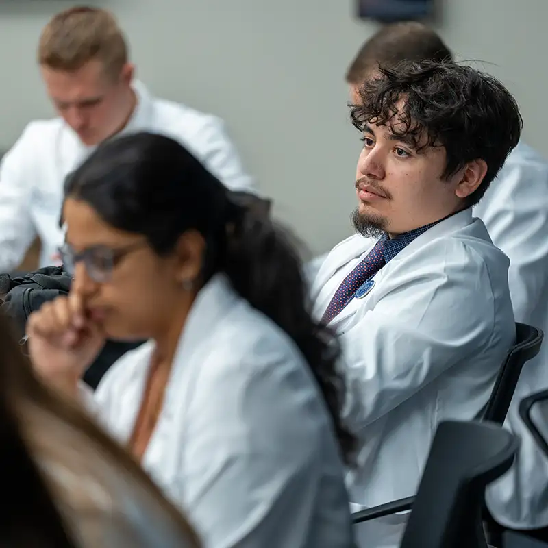 Medical school student in lab coat sitting in class